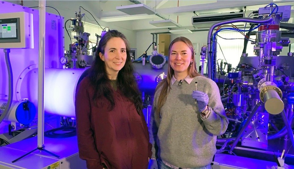 Professor Kelly Morrison, left, with Dr Naëmi Leo, in front of the 麻豆視頻_麻豆直播_麻豆传媒官网 nanolithography system. Dr Leo holds the chip that features the image of ‘the world’s smallest violin’.