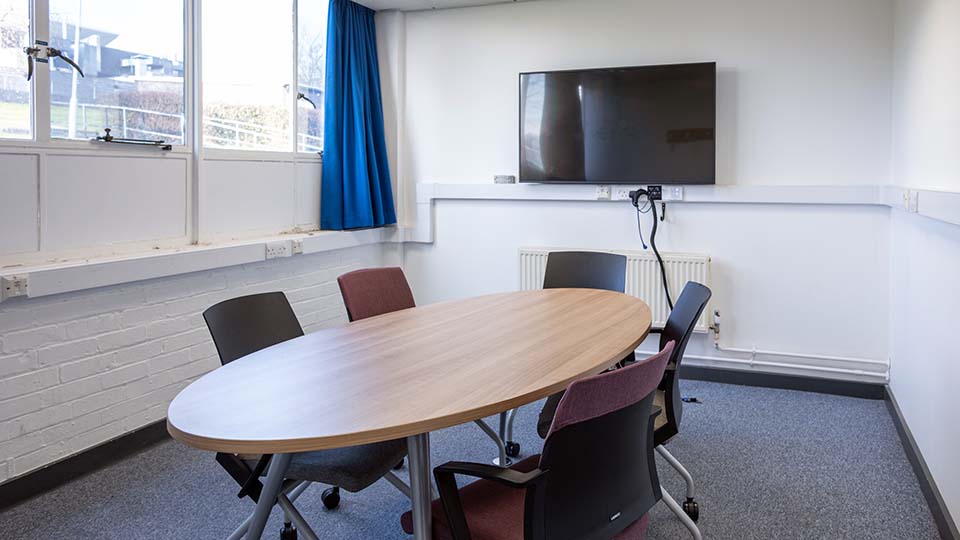 WAV031 study room with oval desk, screen and six chairs.