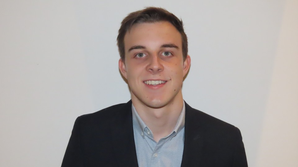 A headshot of Sam Jeffery in a suit