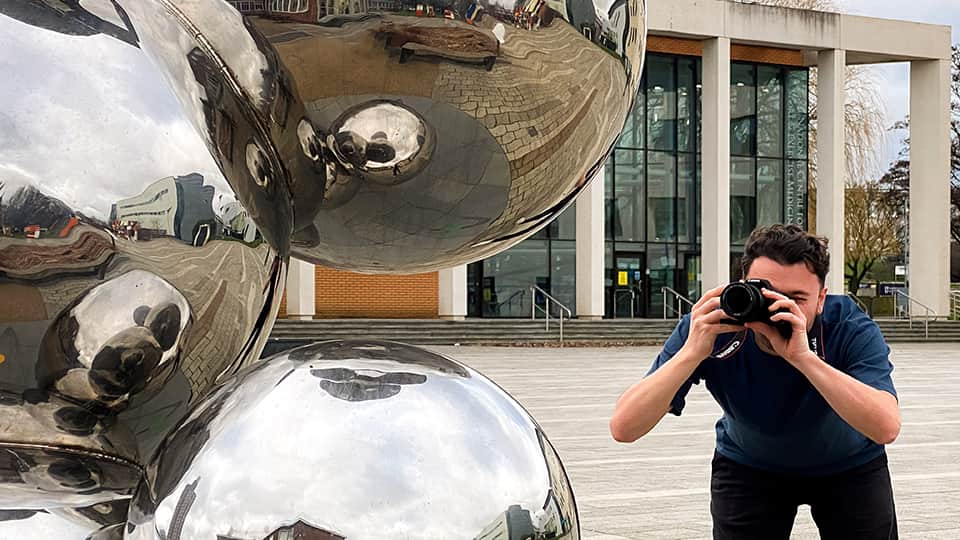A man taking a picture of a sculpture.