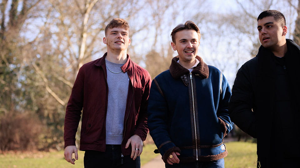 Three students walking together in a park.