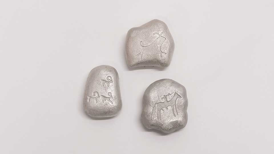 Three silver brooches engraved with symbols of animals.
