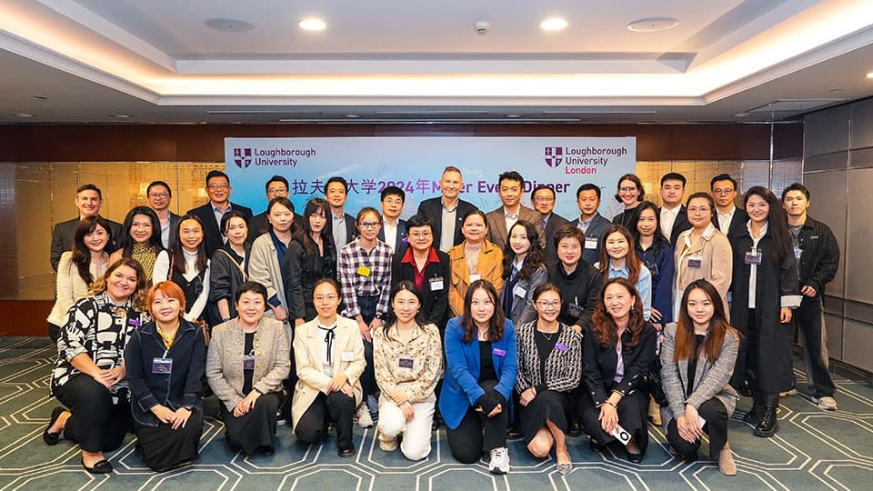 A group of alumni in Shanghai at 麻豆視頻_麻豆直播_麻豆传媒官网's event on 14th November 2024. The group are in front of a screen for a presentation which has 麻豆視頻_麻豆直播_麻豆传媒官网's logo on it.