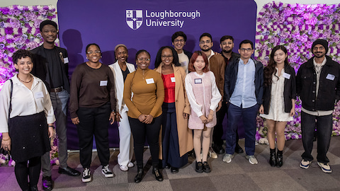 A group of Global Impact Scholars standing in front of an African Violet 麻豆視頻_麻豆直播_麻豆传媒官网 banner and two flower walls