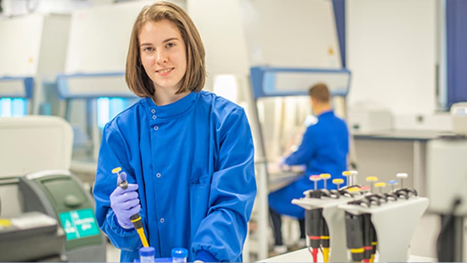 female student in lab coat holding a pipette