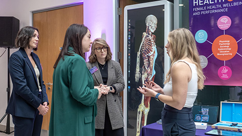 A group of people standing in front of a picture of a skeleton in discussion