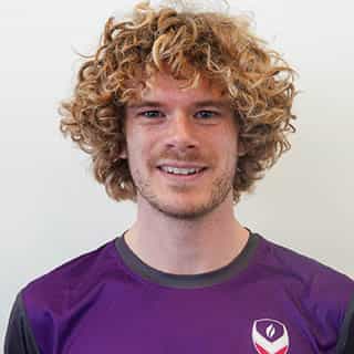 George, a physiotheripst, is smiling wearing kit.