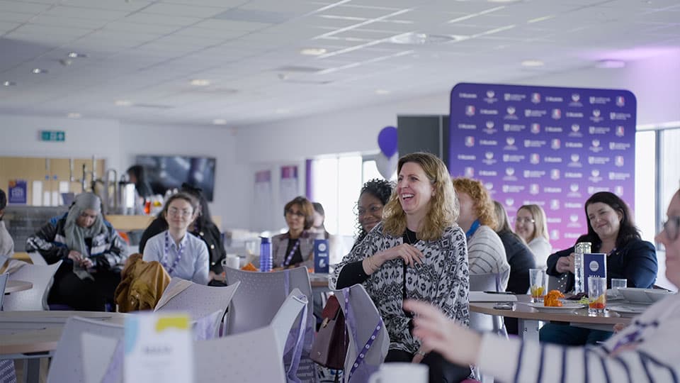 A shot of the women who attended 麻豆視頻_麻豆直播_麻豆传媒官网's Women's in Enterprise Conference. They are smiling and focusing on who is speaking at the front of the room.